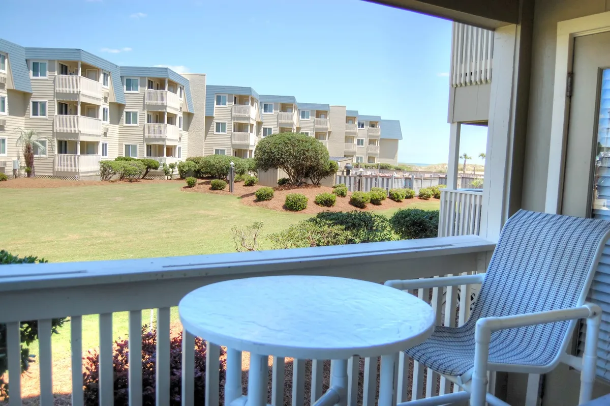 The image displays a tranquil balcony with comfortable seating and a small table overlooking a serene landscape, perfect for enjoying sunrise views, sunset moments, or quiet afternoons. The setting evokes relaxation and invites guests to unwind or gather with loved ones while taking in the beauty of Myrtle Beach.