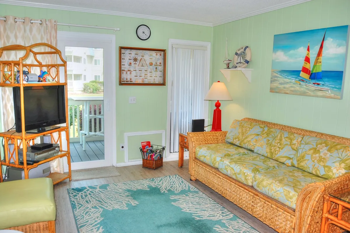 An alternative angle of the living area, showing a floral-patterned sofa, sailboat artwork, and a television stand. The warm lighting and decor evoke a sense of comfort, ideal for relaxing, reading, or enjoying coffee.